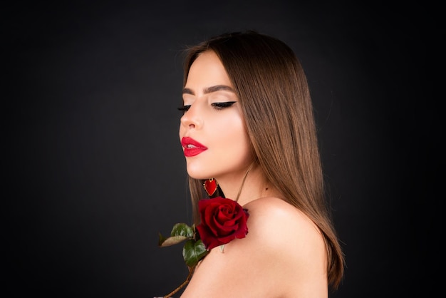 Femme aux lèvres rouges et fleur rose sur fond noir isolé Mode beauté portrait sur fond de studio