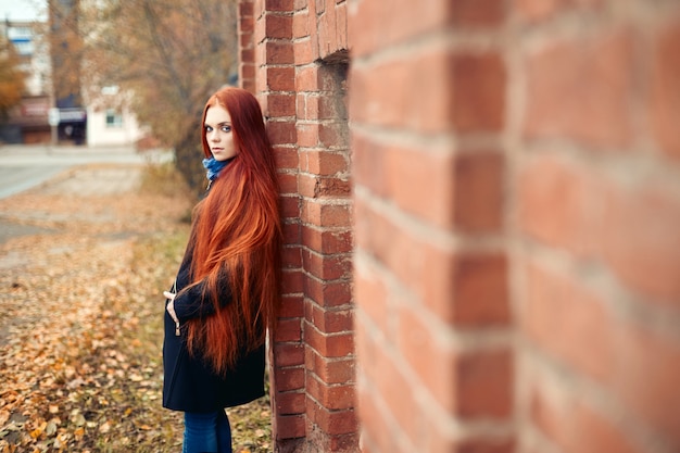 Femme aux longs cheveux roux se promène en automne