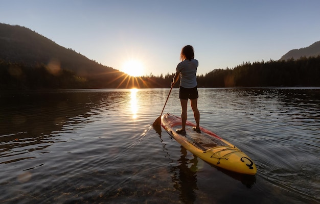 Femme aventureuse pagayant sur un paddle board dans un lac paisible