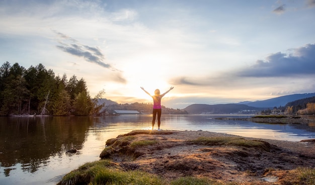 Femme aventureuse sur un rivage appréciant le coucher du soleil coloré