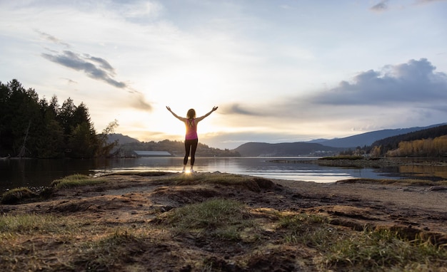 Femme aventureuse sur un rivage appréciant le coucher du soleil coloré