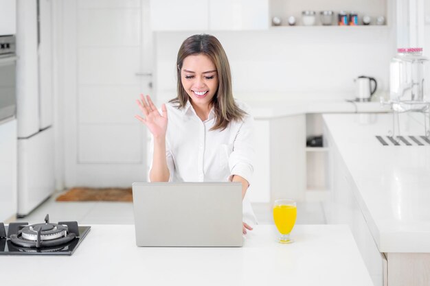 Femme ayant un appel vidéo avec des amis tout en travaillant