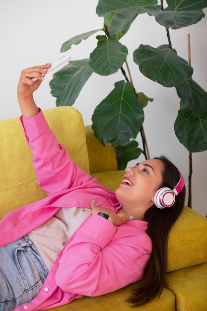 Photo femme ayant un appel vidéo sur smartphone alors qu'elle était assise sur le canapé à la maison