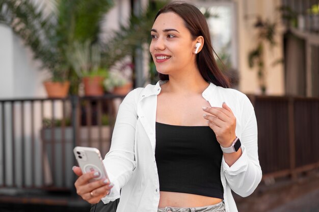 Photo femme ayant un appel vidéo sur smartphone tout en étant à l'extérieur de la ville