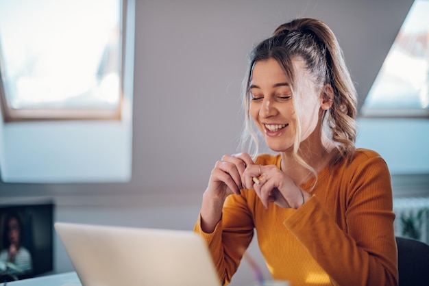 Femme ayant un appel Web sur un ordinateur portable tout en travaillant à la maison