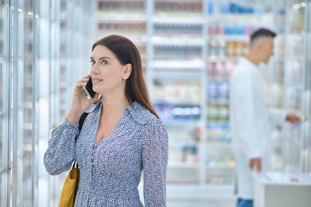 Femme ayant une conversation téléphonique dans une pharmacie