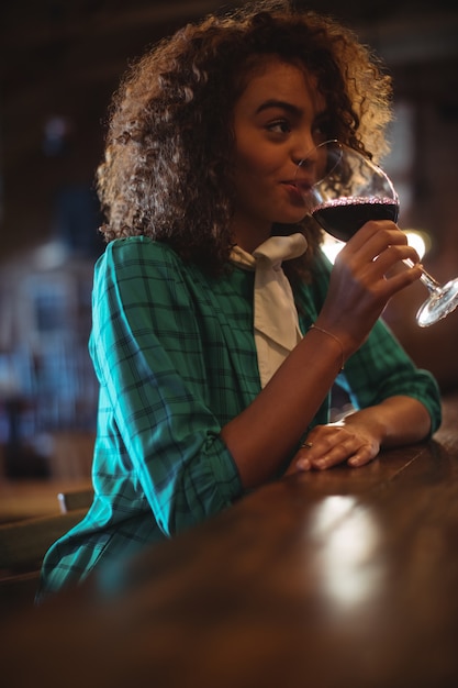 Femme ayant du vin au comptoir du bar