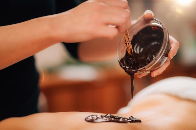 Femme ayant un massage du dos au chocolat dans un centre de bien-être