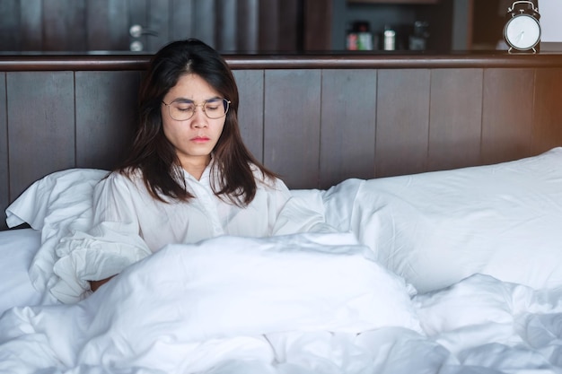 Femme ayant des migraines pendant qu'elle est allongée dans son lit à la maison insomnie souffrance fatiguée sans sommeil et concepts stressés