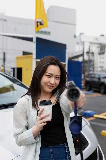 Photo femme ayant une pause-café pendant que sa voiture électrique est en charge