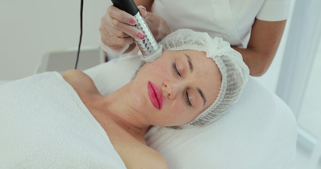 Femme ayant un soin du visage stimulant. Femme se soulevant rf dans un salon de beauté. Visage de soins de la peau.