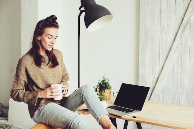 Femme ayant un verre avec un ordinateur portable à la table