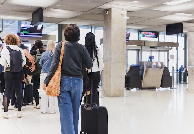 Une femme avec des bagages dans une file à l'aéroport