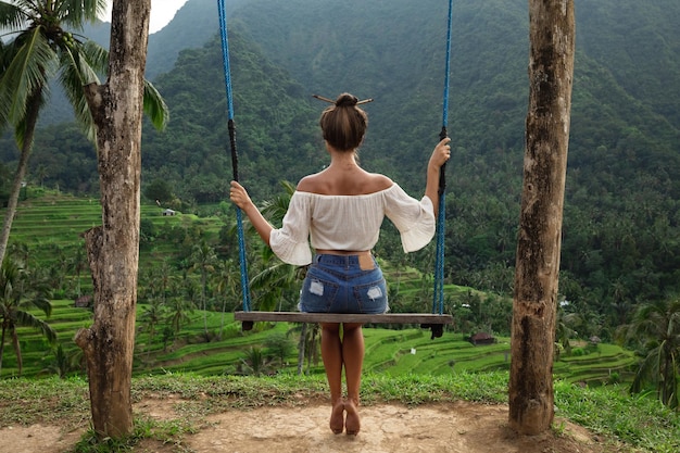 Femme sur des balançoires avec une belle vue sur les rizières en terrasses de Bali