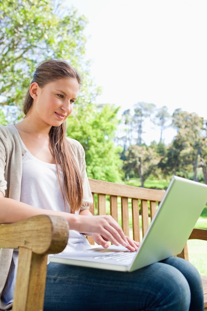 Photo femme sur un banc de parc avec son ordinateur portable