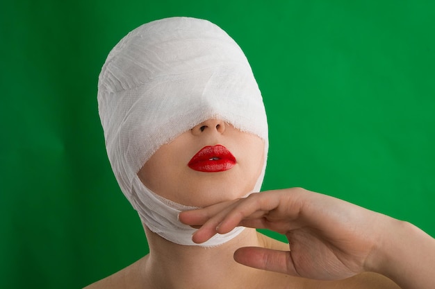 La femme avec un bandage sur la tête et les lèvres pose sur fond de chromakey