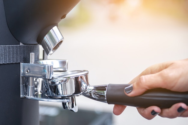 Femme barista broyer les grains de café dans le porte-filtre