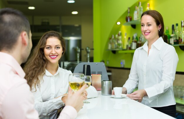 Femme barista et deux clients au café