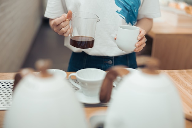 Femme barista tenant une tasse en verre et une tasse de café