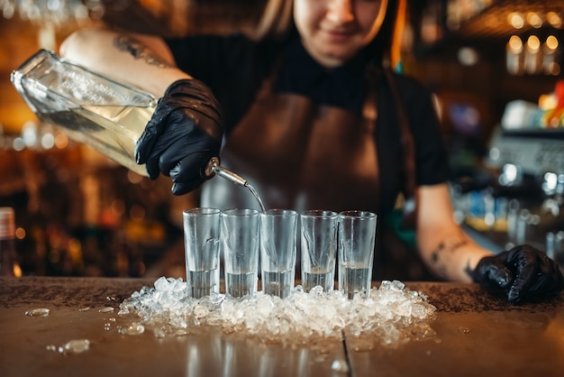 Femme barman en gants met des boissons sur la glace