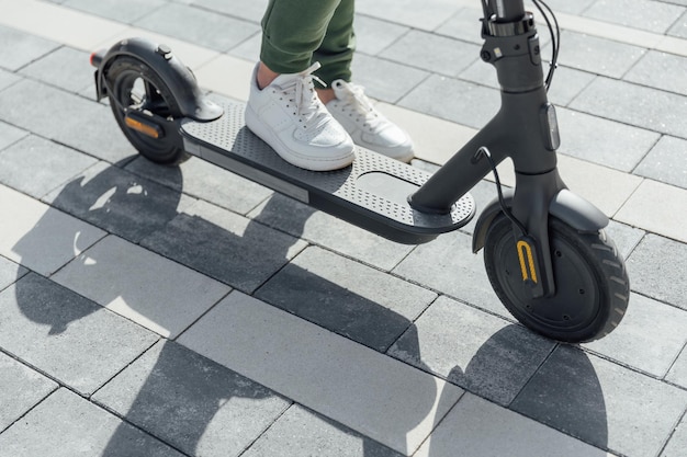 Photo une femme en baskets blanches se tient sur un scooter électrique