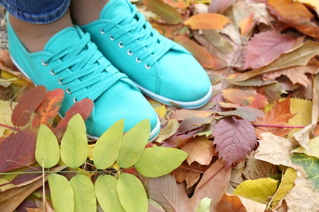 Femme en baskets bleues debout sur le feuillage