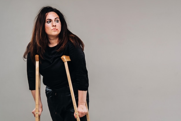 Une femme battue en vêtements noirs avec des roulettes dans ses mains sur un fond gris.