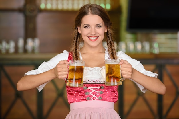 Photo femme de beau serveur sexy tenant des verres de bière.