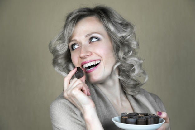 Une femme avec un beau sourire mange des bonbons.