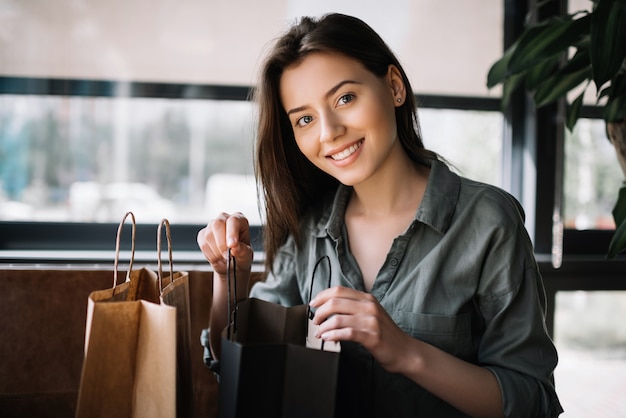 Femme avec beau sourire ouvert sacs à provisions. Blogger déballage cadeau