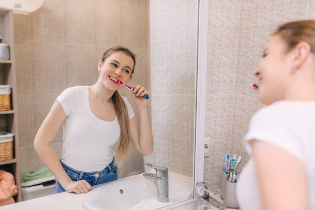 Une femme avec un beau sourire se brosse les dents éco avec une brosse en bambou.