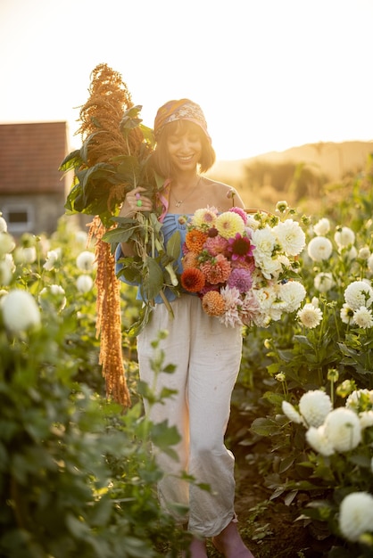 Femme avec beaucoup de fleurs sur la ferme de dahlia à l'extérieur