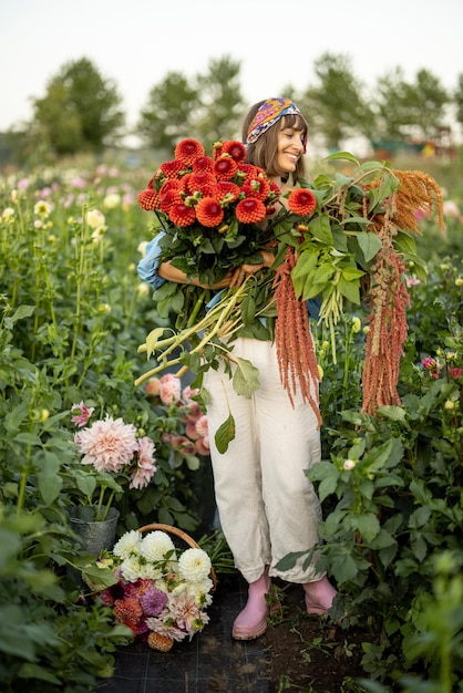 Femme avec beaucoup de fleurs sur la ferme de dahlia à l'extérieur