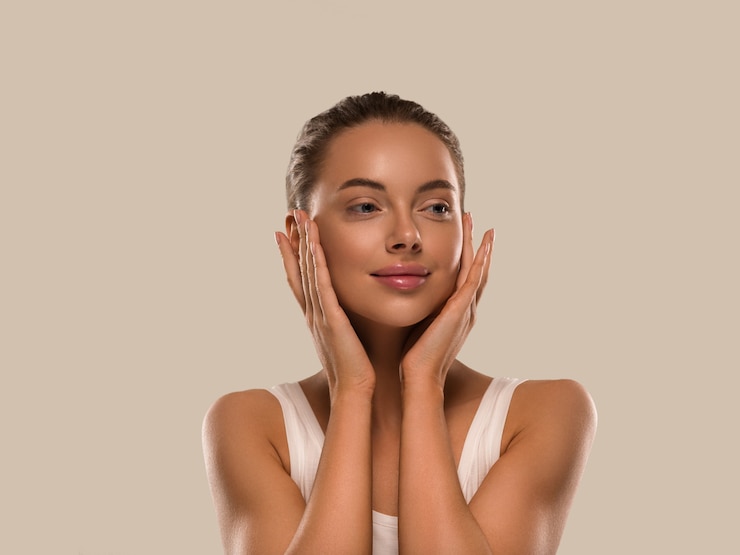 Photo femme de beauté avec des mains en bonne santé maquillage naturel propre peau fraîche concept fond de couleur marron