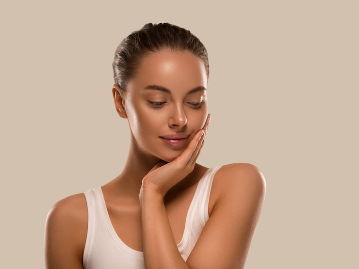 Photo femme de beauté avec des mains en bonne santé maquillage naturel propre peau fraîche concept fond de couleur marron