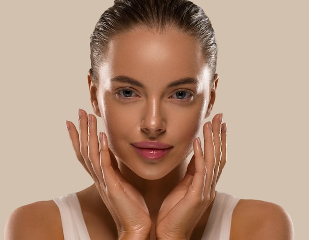 Femme de beauté avec des mains en bonne santé maquillage naturel propre peau fraîche concept fond de couleur marron