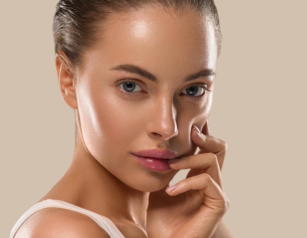 Femme de beauté avec les mains maquillage naturel sain propre peau fraîche concept couleur fond marron