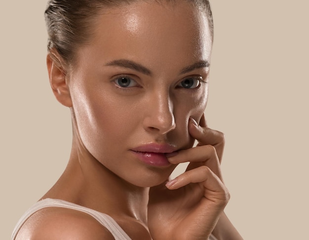 Femme de beauté avec les mains maquillage naturel sain propre peau fraîche concept couleur fond marron