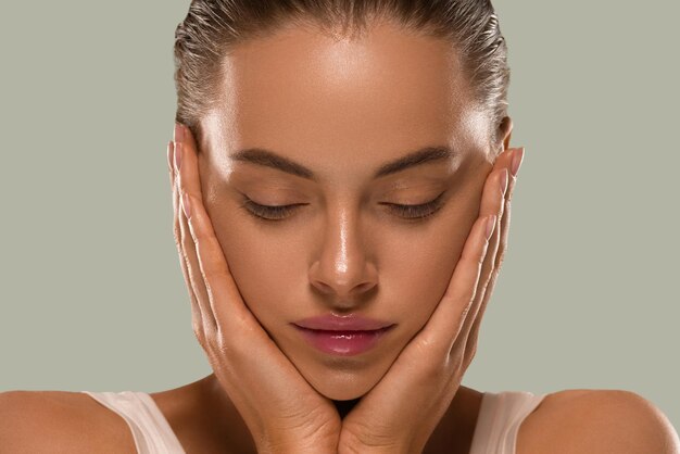 Femme de beauté avec les mains maquillage naturel sain propre peau fraîche concept couleur fond vert