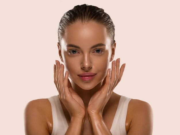 Femme de beauté avec les mains naturelles saines composent le concept de peau fraîche et propre fond de couleur jaune