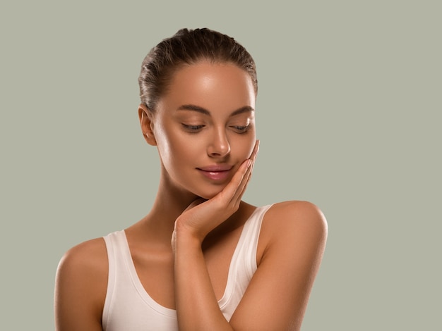 Femme de beauté avec les mains naturelles saines composent la peau fraîche propre concept de fond couleur vert