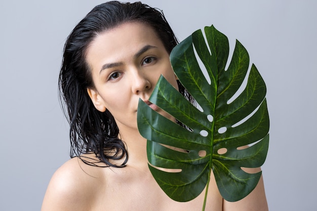 Femme de beauté avec le portrait de feuille de palmier vert naturel Cosmétiques de maquillage de beauté de mode