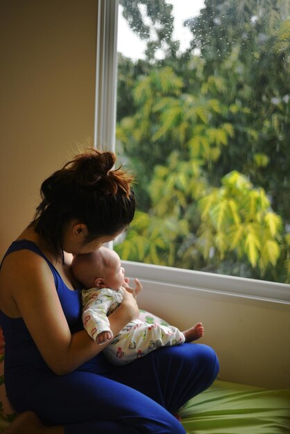 Photo femme et bébé assis à l'intérieur