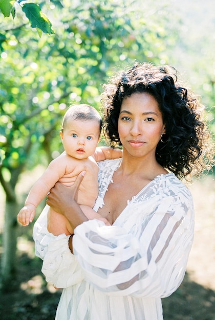 Femme avec un bébé dans ses bras dans un jardin verdoyant