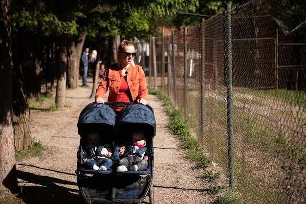 Femme avec bébé poussette promenades dans le parc