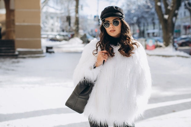 Une femme belle, élégante et à la mode dans un manteau de fourrure, un chapeau et des lunettes