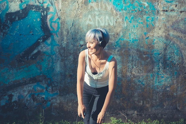 femme belle jeune hipster cheveux bleus courts avec des écouteurs musique