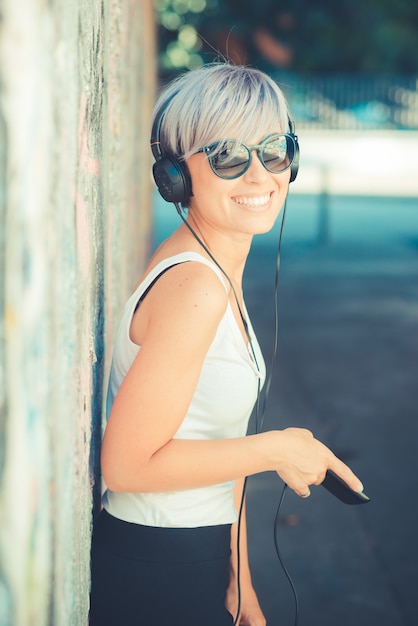 femme belle jeune hipster cheveux bleus courts avec des écouteurs musique