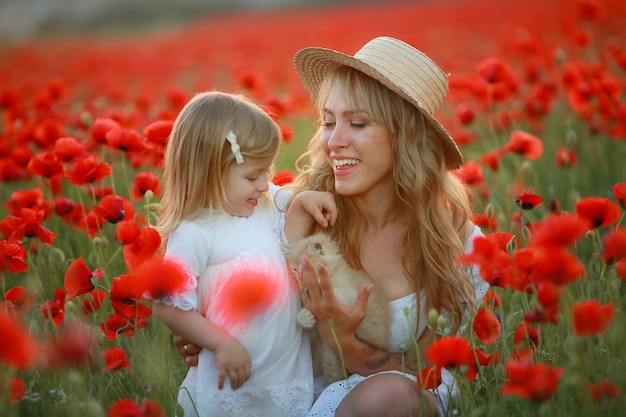 Femme belle maman blonde avec bébé dans les bras dans les coquelicots