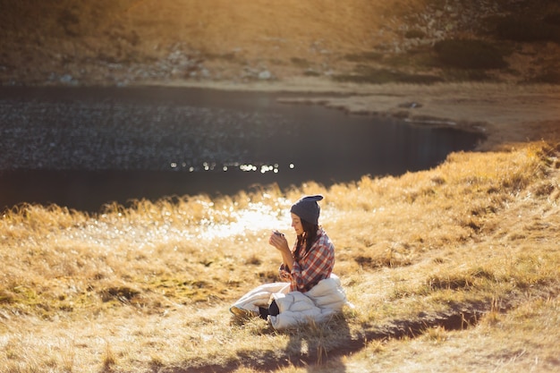 Femme belle voyageuse randonnée dans les montagnes avec une tasse de boisson près du lac camping voyage